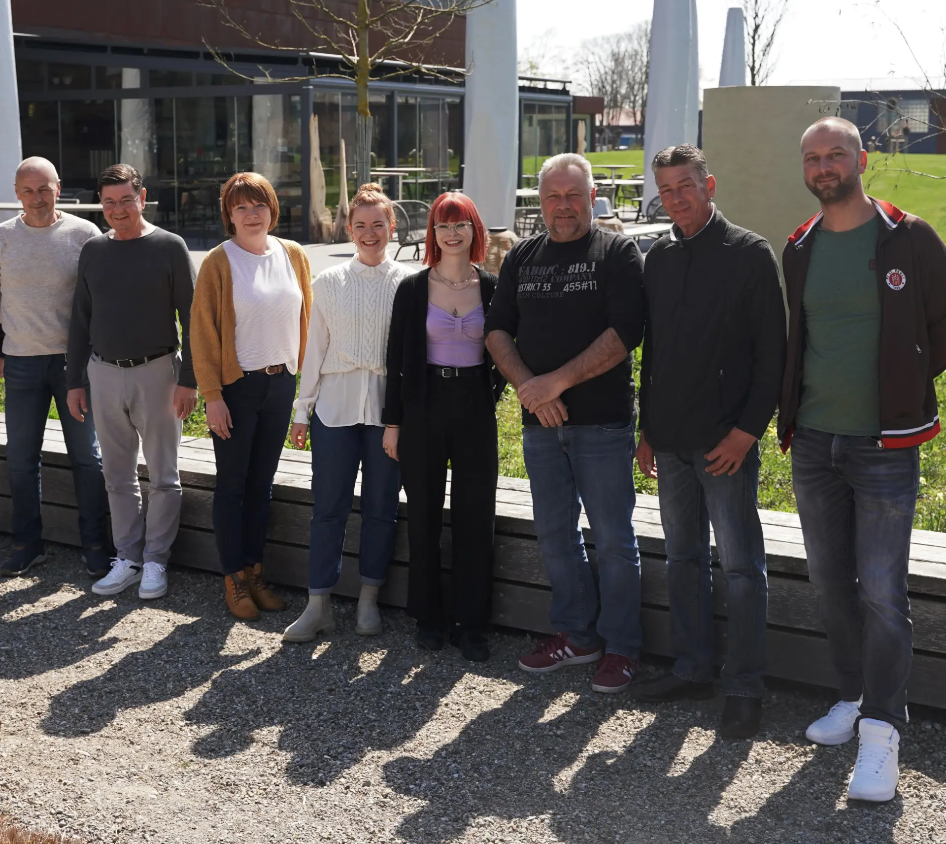 Das Team der DeWiTec GmbH, acht Leute nebeneinander im Freien in der Frühlingssonne